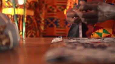 Turuncu ceketli Afro-Amerikan terzi gündüzleri dikiş atölyesinde çalışırken mavi tekstili makasla kesiyor.