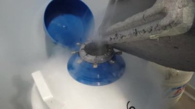 Donmuş yumurta hücreleri ve üreme kliniğindeki embriyolarla birlikte kriyojenik bir tank kabından azot sıvısı sıçrıyor.