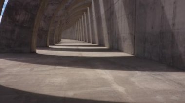 Drone view of archway with stone curved columns and shadows creating effect of optical illusion on sunny day