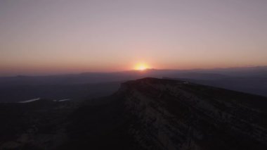Aerial view of picturesque landscape of mountainous valley against colorful sky with sun setting over horizon