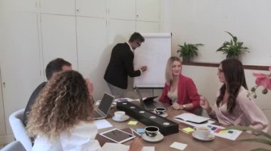 Modern çalışma alanındaki iş toplantısında akıllı patron resim çizelgesi gösteriyor ve yöneticilerle konuşuyor