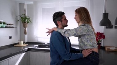 Sevgiliyi kucaklayan, tezgahta oturan, öpüşen ve birlikte zaman geçiren erkek arkadaşın yan görüntüsü.