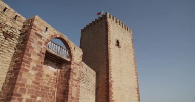 Güneşli bir günde mavi bulutsuz gökyüzünün arka planında taş cepheli kuleleri olan eski kalenin sol alttan görünüşü