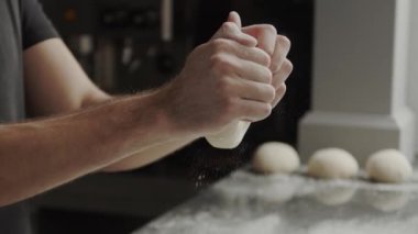 Çağdaş kafe mutfağında yemek pişirirken yumuşak hamurdan topa şekil veren tanınmayan erkek şef.
