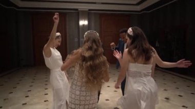 Neşeli, çoklu etnik çeşitlilikte yeni evliler ve konuklar düğün gününü kutlarken geniş salda dans ediyorlar.