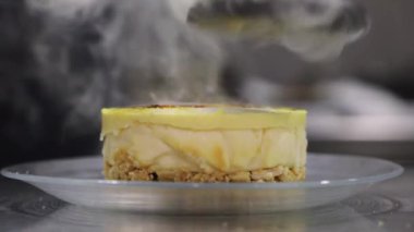Kafenin mutfağındaki masaya yerleştirilmiş lezzetli cheesecake 'in üzerinde yüzsüz aşçının karamelize şekeri yakın plan görüntüsü.