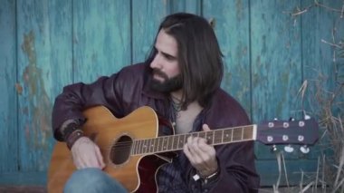 Müzisyen yan yan yana oturup gitar çalıyor.