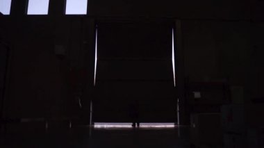 İsimsiz bir işçi deponun kapısını açıyor.