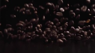 Lezzetli sıcak içeceğin içeriği olarak koyu fona dökülen kavrulmuş kahve çekirdekleri.