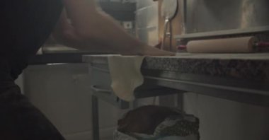 Mahsul erkek aşçı un tozu masasında pizza pişirirken hamur esnetmeye başlıyor.