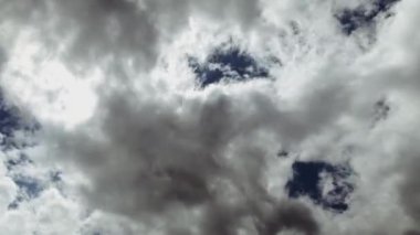 Mavi gökyüzü, parlak güneş ve hızlı hareket eden beyaz bulutların altında.