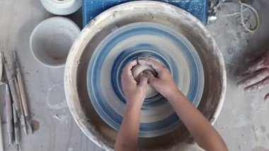 Yukarıdan gelen, tanınmayan, siyah günlük kıyafetli, çömlek tekerinin yanında duran, hafif atölyede küçük bir kızla kil çömleği şekillendirirken...