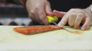Tanınmayan aşçı Asya restoranında çalışırken somonu bıçakla kesiyor.