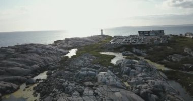 Peggys Koyu Deniz feneri ve otoparkı ile Kanada 'da sabah dalgalanan denizin yanında bulunan arabalarla kayalık sahilin insansız hava aracı görüntüsünü yükseltin.
