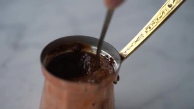 Geleneksel Türk kahve demliğinde demleme sırasında metal kaşıkla kahve karıştırma süreci yüksek açılı yakın çekim süreci
