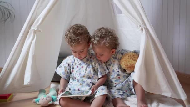 Adoráveis Irmãos Gêmeos Roupas Semelhantes Assistindo Vídeo Tablet Enquanto Sentado — Vídeo de Stock