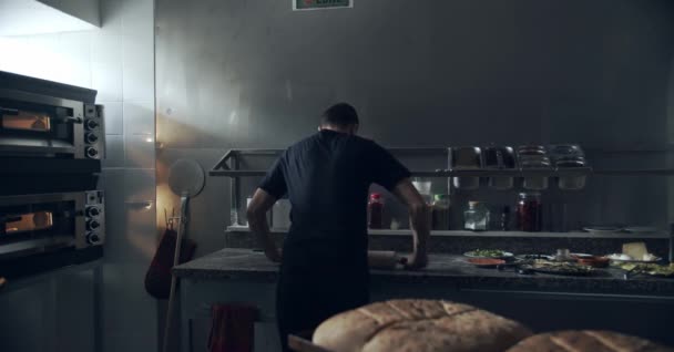 在厨房准备披萨时 匿名男子用滚动别针将新鲜面团铺在大理石桌上的倒影 — 图库视频影像