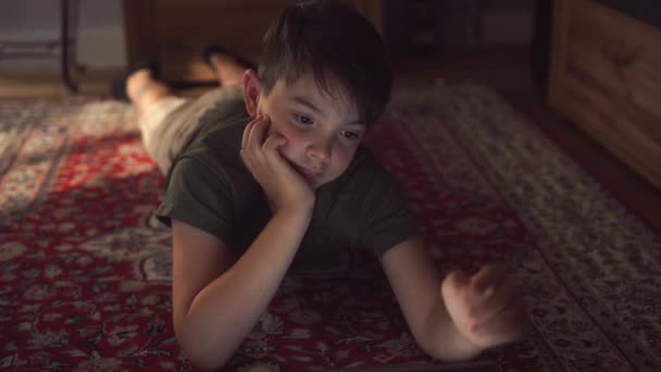 Pensive Little Boy Casual Clothes Lying Floor Hands Chin Watching — Stock Video