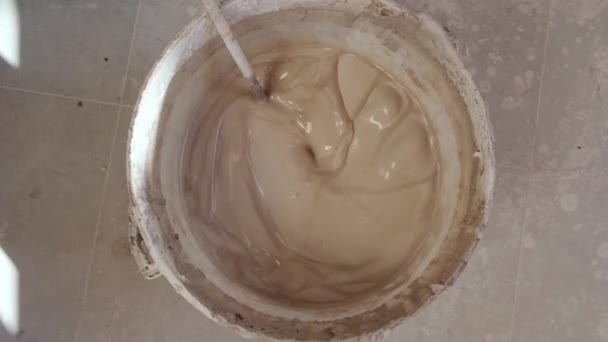 陶器工房の床に置かれた混合パドルでバケツで粘土を準備するマスターのトップビュー — ストック動画