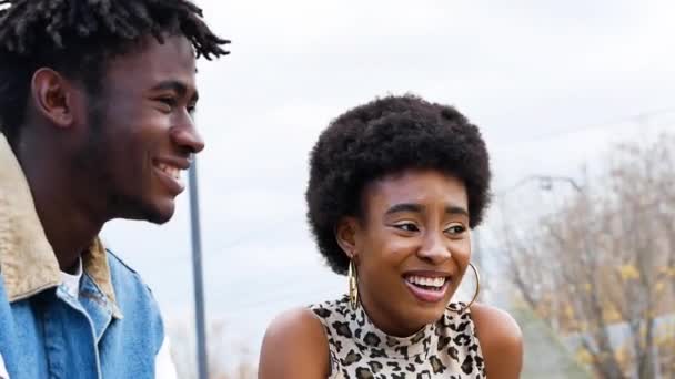 现代的非洲裔美国夫妇 卷曲的头发 穿着时髦的斜纹棉布衣服 一边笑着一边看一边站在城市街道上 — 图库视频影像