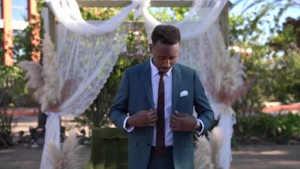 アフリカ系アメリカ人の新郎は 式の前に結婚式の日に庭に立って離れて見て — ストック動画