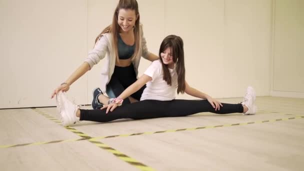 Glimlachende Vrouwelijke Trainer Sportkleding Helpt Vrolijk Meisje Met Stretching Benen — Stockvideo
