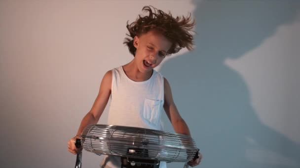 Jongen Houdt Een Lopende Ventilator Zijn Handen Terwijl Hij Schreeuwt — Stockvideo