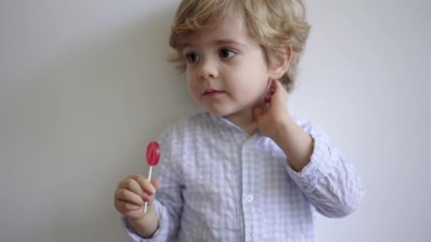 Niño Adorable Con Pelo Rubio Disfrutando Sabrosa Piruleta Roja Mientras — Vídeos de Stock