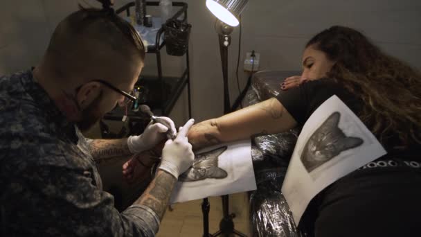 Fiatal férfi tetováló gép és a tetoválás fekete tintával szalonban