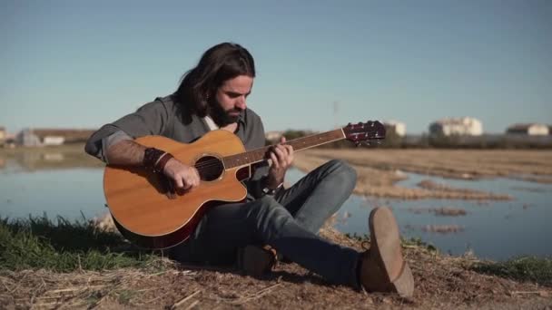 Man Spelar Gitarr Äng Nära Sjön — Stockvideo