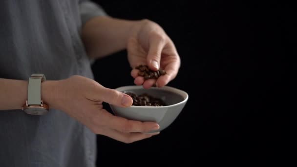 작물인 커피콩을 손에서 그릇에 검은색 배경에 서서히 모습을 가까이 — 비디오