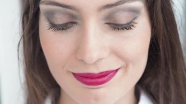 Closeup of charming female with pink lips and black mascara standing in beauty salon while smiling and looking at camera