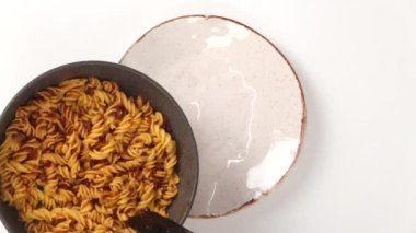 Kimliği belirsiz şahsın yakından bakınca tavadan tavaya domates soslu lezzetli, taze pişmiş makarna koyduğunu görüyoruz.