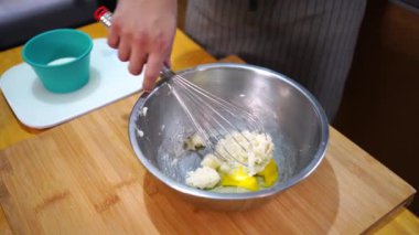 Kesilmiş anonim insan şekerli ve tereyağlı çiğ yumurtaları paslanmaz bir kaseye yerleştiriyor.