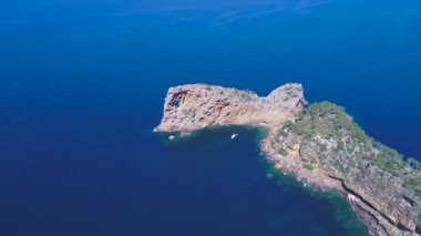 Zoom out drone view of see bay with green rocky hills on coast