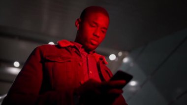 Hareket halindeki merdivenlerde telefonu olan siyah bir adam.