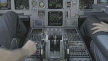 Anonim erkek kaptan ve pilotun arka planda modern uçağın kokpitinde oturup kalkışa hazırlanırken ekipmanları kontrol etmesi.