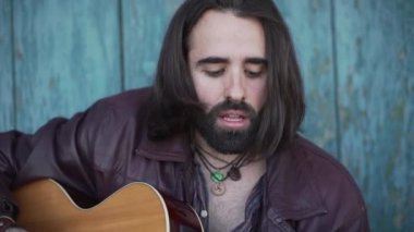 Müzisyen yan yan yana oturup gitar çalıyor.