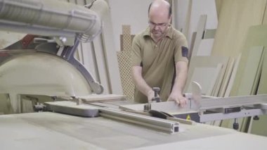 Dikkatli marangoz atölyede budama makinesi kullanarak odun kesiyor.