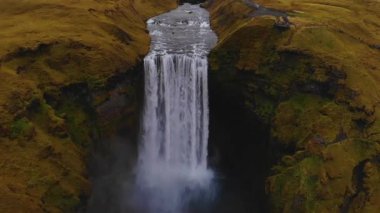 İzlanda 'daki yeşil uçurumdan düşen geniş Skogafoss şelalesinin havadan görüntüsünü büyüt