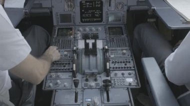 Anonim erkek kaptan ve pilotun arka planda modern uçağın kokpitinde oturup kalkışa hazırlanırken ekipmanları kontrol etmesi.