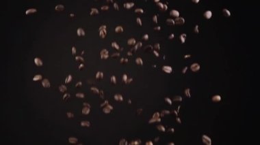 Lezzetli sıcak içeceğin içeriği olarak koyu fona dökülen kavrulmuş kahve çekirdekleri.