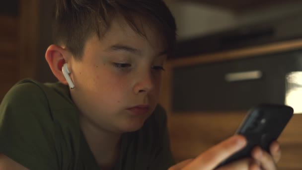 Niño Concentrado Camiseta Verdaderos Auriculares Inalámbricos Acostado Alfombra Casa Viendo — Vídeos de Stock