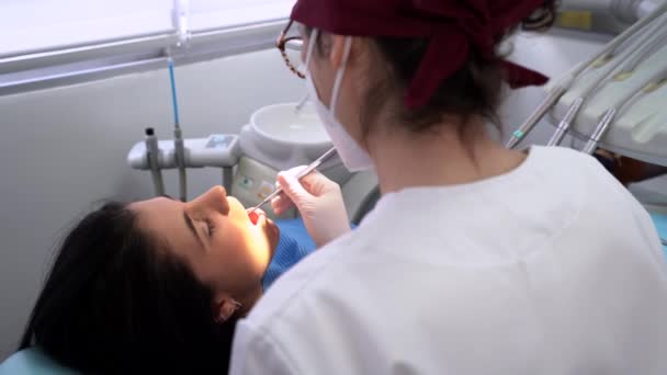 Crop Profesjonalny Dentysta Mundurze Maską Medyczną Wiercenie Zęba Spokojnej Kobiety — Wideo stockowe