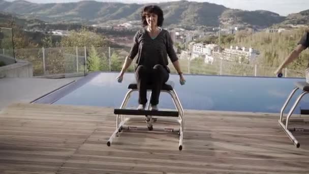 Olgun Bir Kadın Pilates Sandalyesinde Oturuyor Gözleri Kapalı Gülümserken Halterlerle — Stok video
