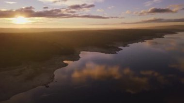 Parlak güneş bataklıkta bulutlu gökyüzünde doğuyor kırsal kesimdeki sakin suyla.