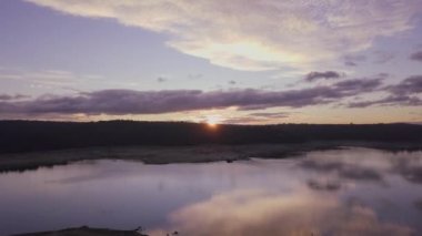 Parlak güneş bataklıkta bulutlu gökyüzünde doğuyor kırsal kesimdeki sakin suyla.
