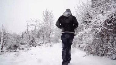 Karlı yolda yürüyen isimsiz bir adam.