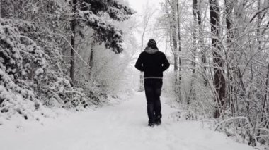 Karlı yolda yürüyen isimsiz bir adam.