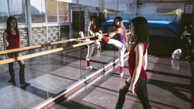 Genç dansçılar stüdyoda birlikte antrenman yapıyor, ısınıyor ve gün ışığında esniyorlar.